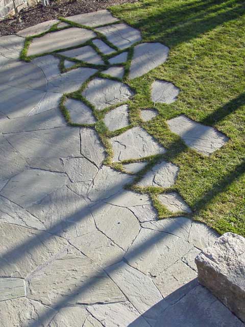 fitted stone patio breaks out onto lawn